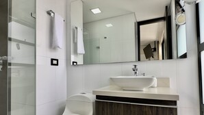 Un bagno moderno con il water bianco, uno specchio grande e un lavabo con mobile contenitore in legno.