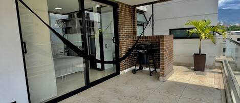 A modern interior with a glass door leading to a living area, a staircase, and a balcony with a grill and a potted plant.