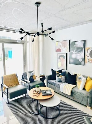 Relax in a stylish living room with a large window, contemporary chandelier, and comfortable seating area.