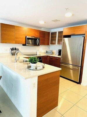 Enjoy cooking in this well-equipped kitchen with a central island, sink, and stainless steel refrigerator.