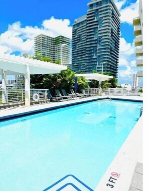 Relax by the pool surrounded by lounge chairs and umbrellas.