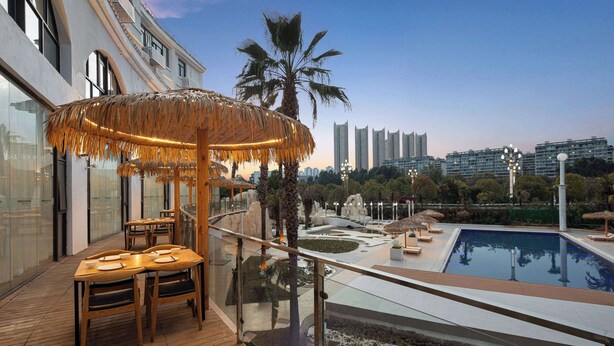 Terraza en la azotea con piscina, zona de comedor y vistas al horizonte de la ciudad.