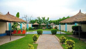 A courtyard with thatched-roof structures, a central seating area, and a stone pathway.