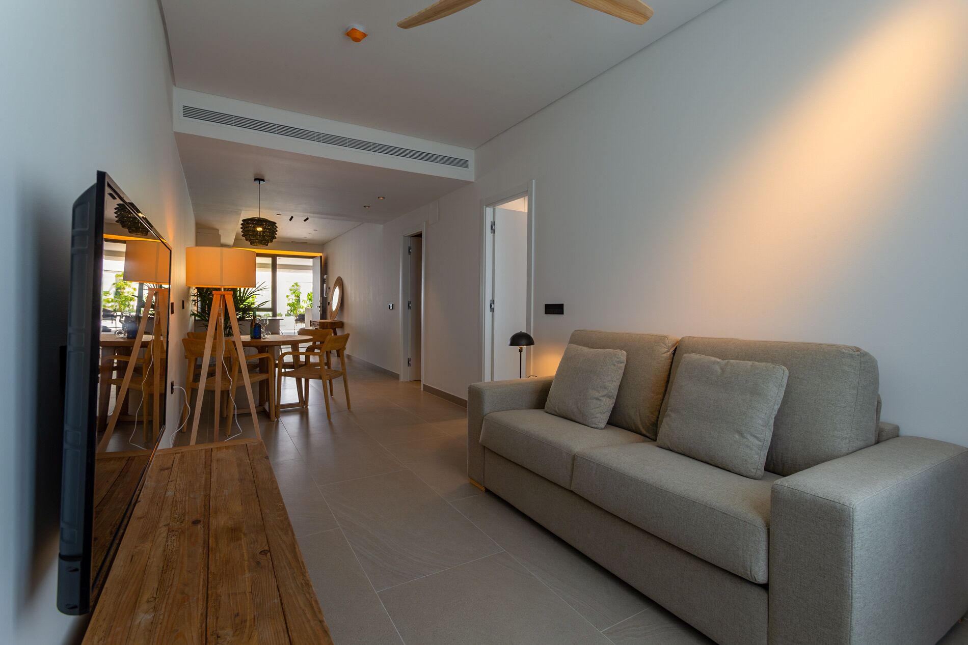 A modern living room with a sofa, wooden floor, and a dining area with a table and chairs.
