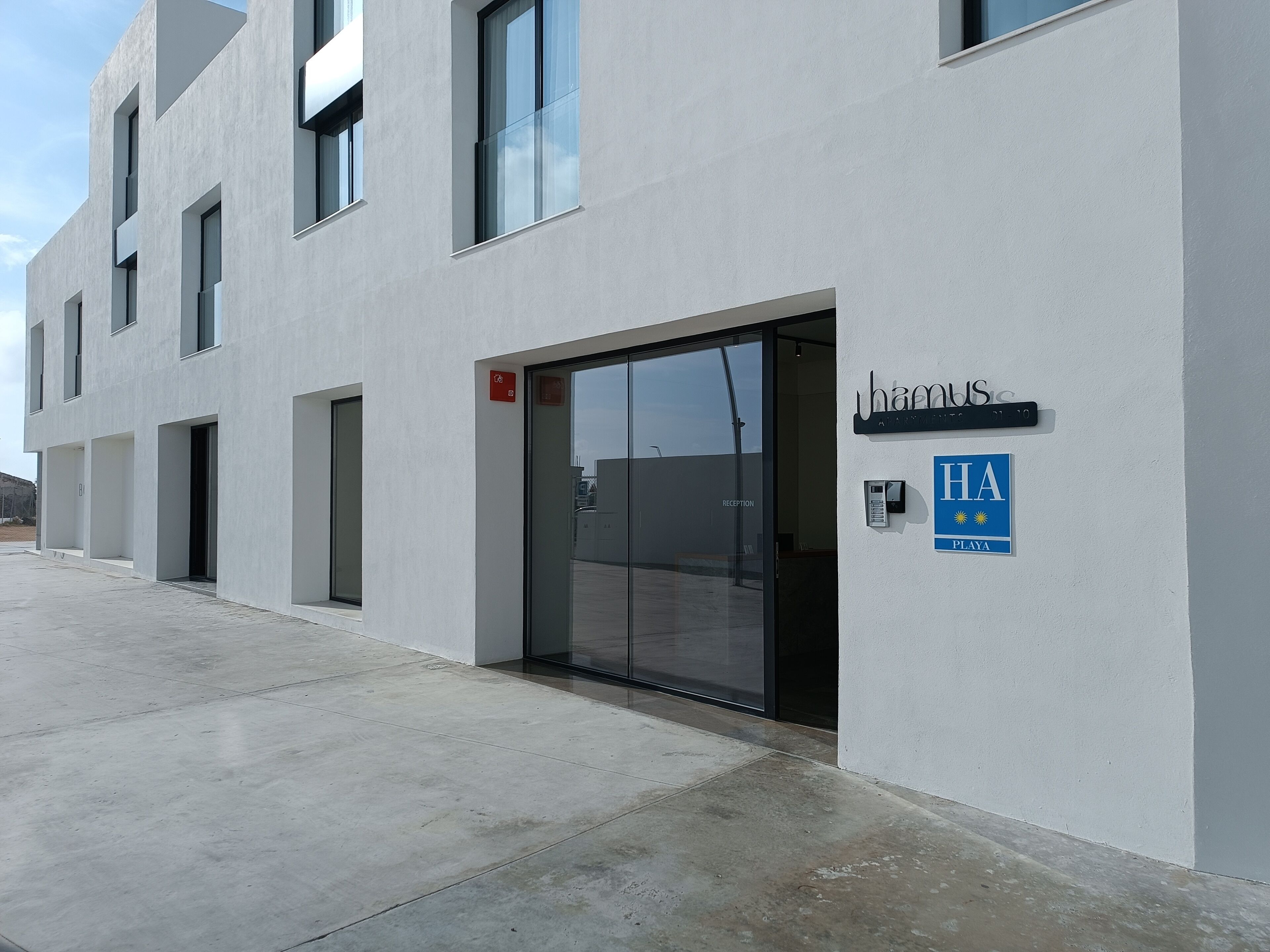 A modern building with a reception area, a sign indicating 'HA Playa', and a wheelchair accessibility symbol.