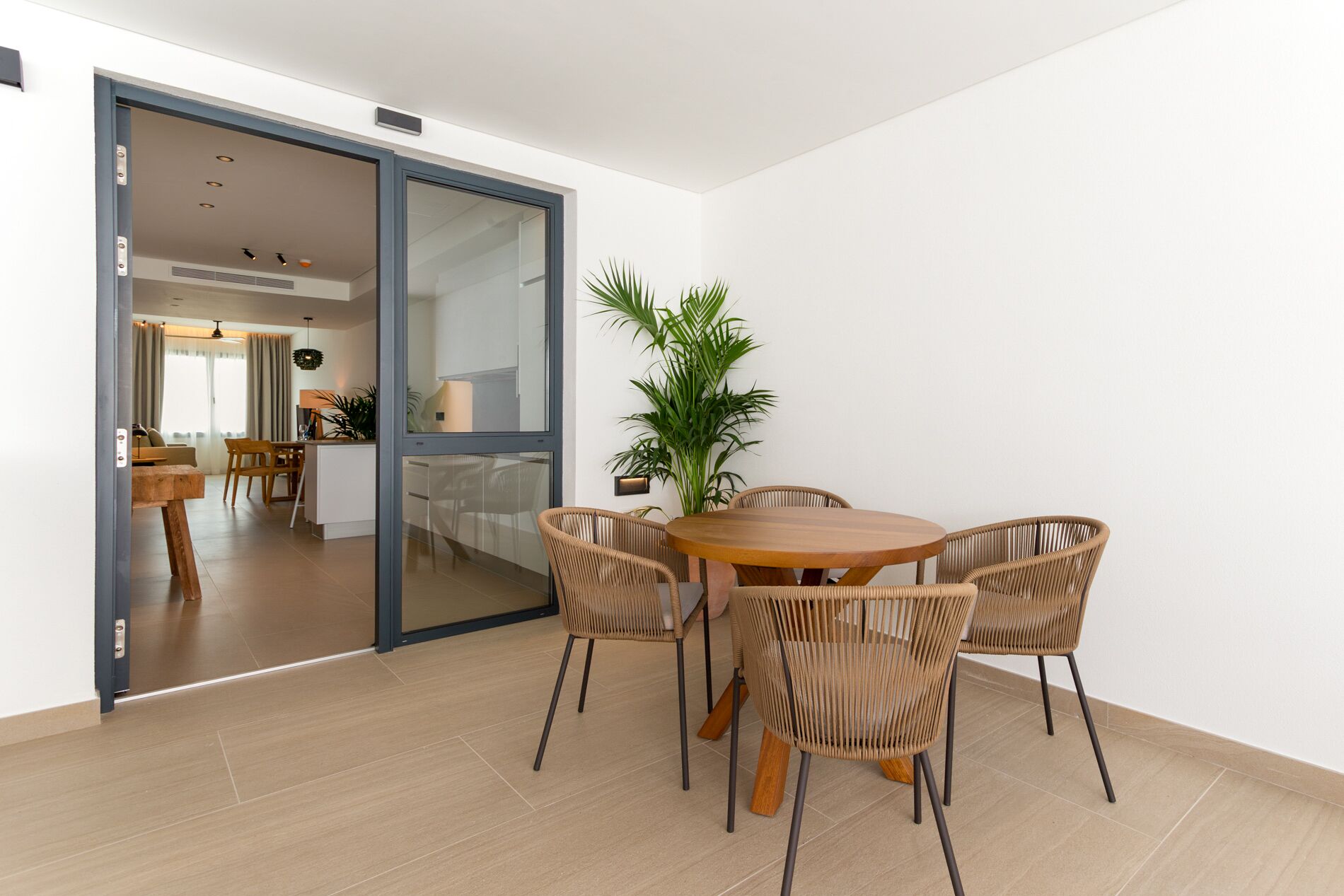 A modern dining area with a round wooden table and four wicker chairs.