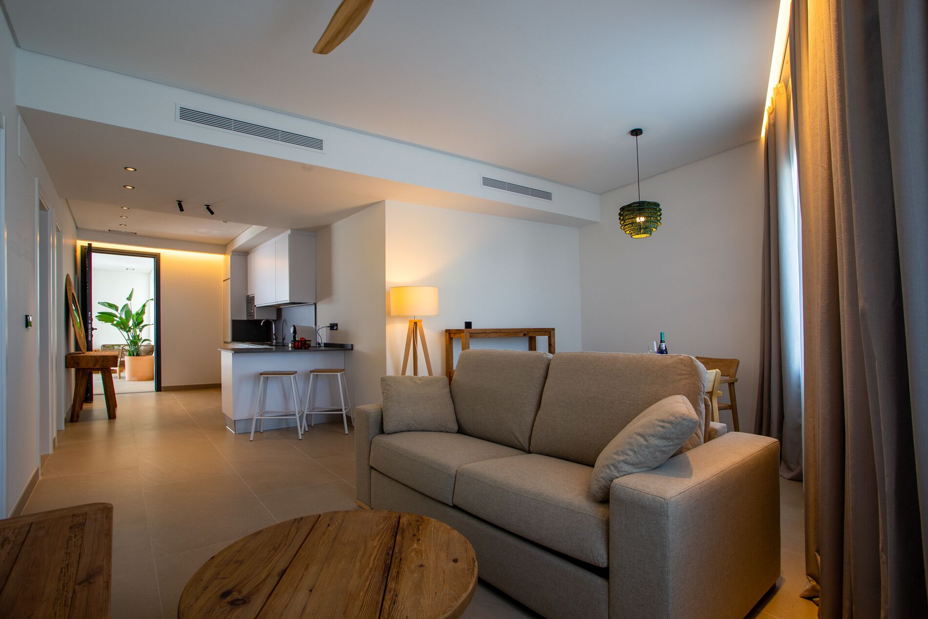 Un salon moderne avec un canapé, une table basse en bois et un coin cuisine à l’arrière-plan.