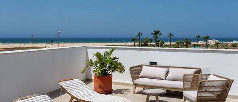 Une terrasse sur le toit, aménagée avec des chaises longues, un canapé et un pot de fleurs.