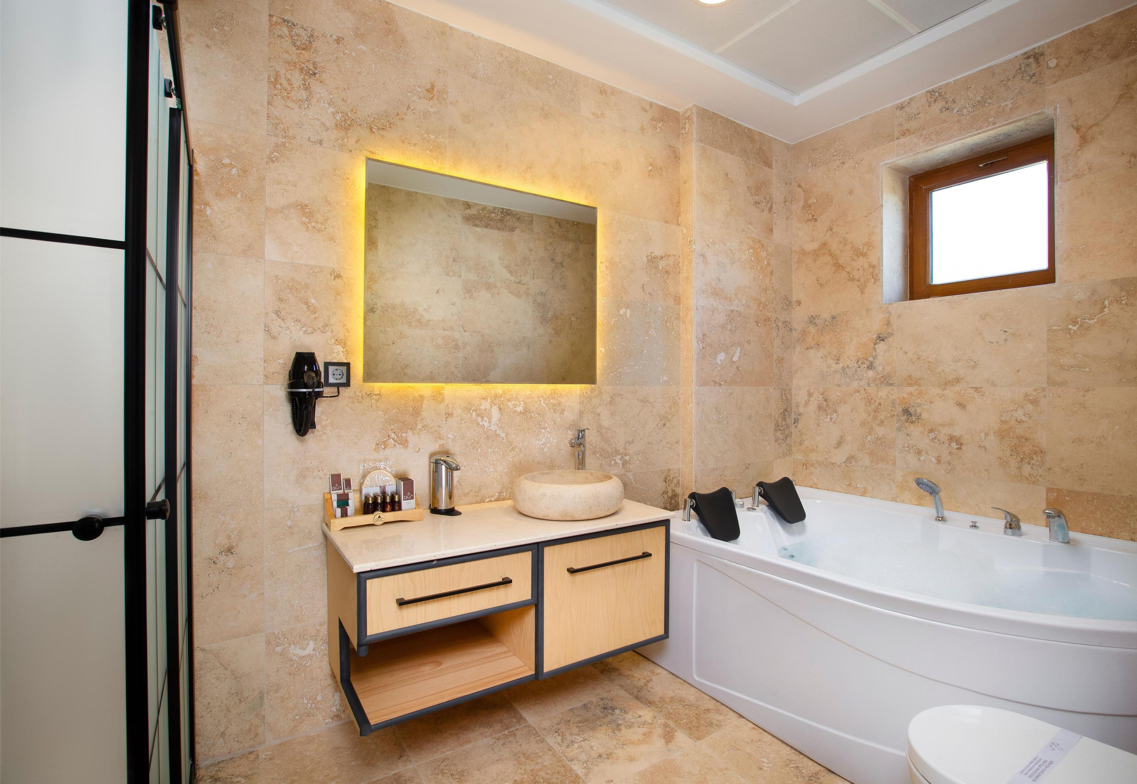 Een moderne badkamer met een vrijstaand bad, een grote spiegel en een wastafelmeubel met wastafel en kast.