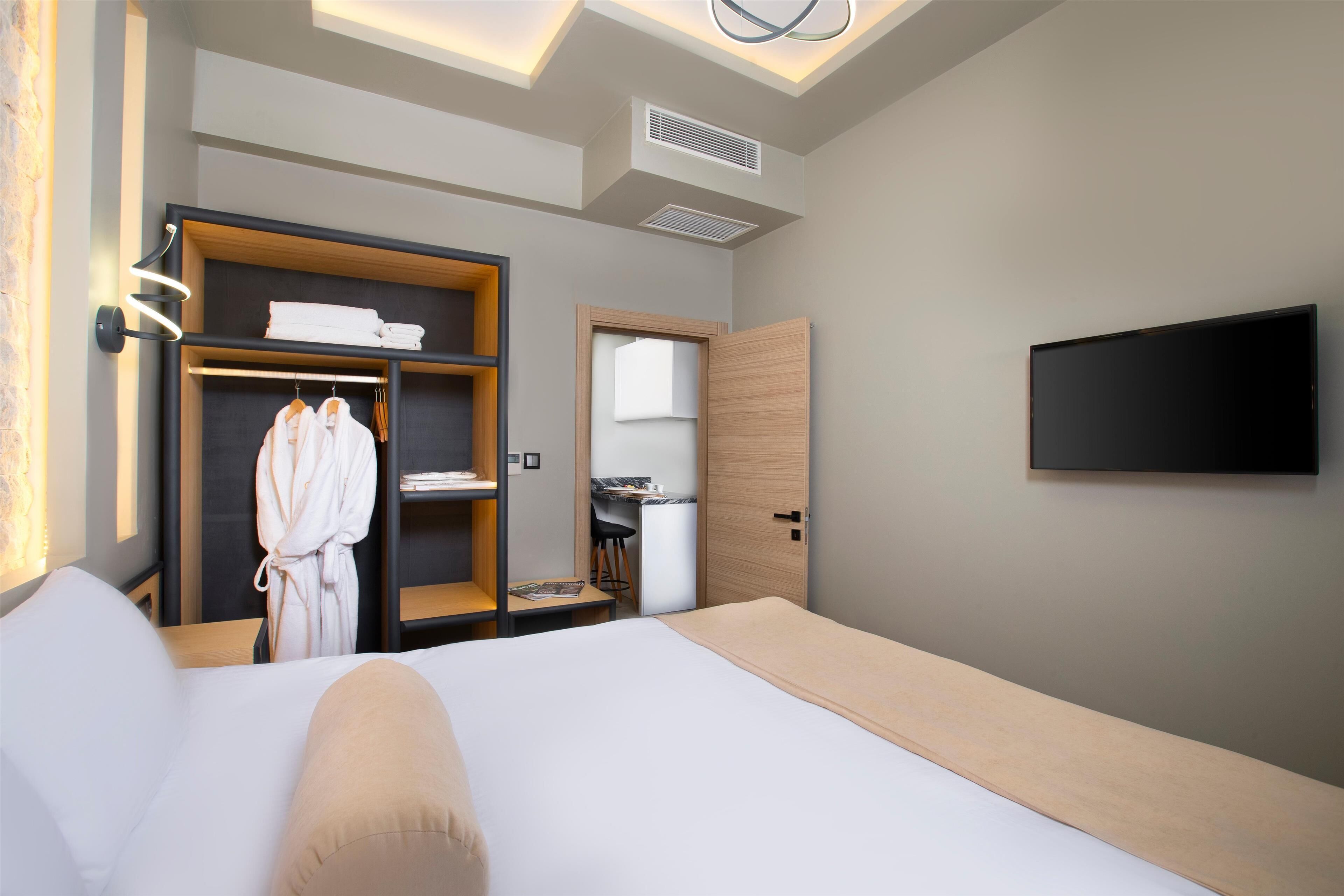 A hotel room with a bed, a wardrobe, a desk, and a TV.
