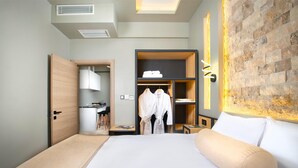 A modern hotel room with a large bed, a wooden wardrobe, a built-in desk, and a brick accent wall. - Cappadocia Acer Living Home (Ürgüp)