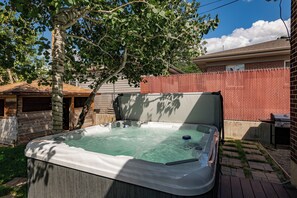 Relax in the backyard hot tub surrounded by a tree and a wooden deck.