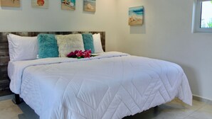 Un letto ben rifatto con una coperta bianca, una testiera in legno e un cuscino decorativo.