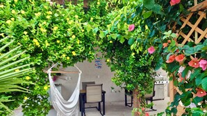 Zona giardino con amaca, sedie e struttura in legno a graticcio.