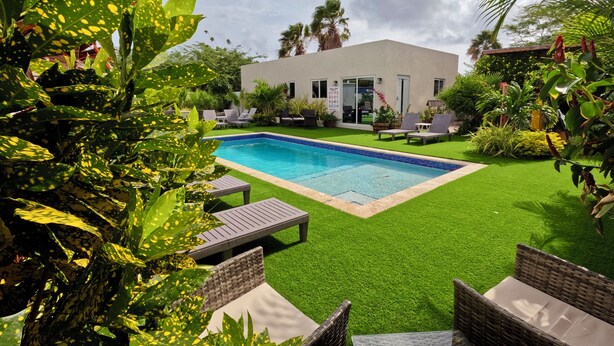 Una moderna casa con piscina, circondata da un lussureggiante verde e mobili da esterno.