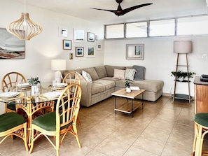 A living room with a sofa, dining table, chairs, and a ceiling fan.