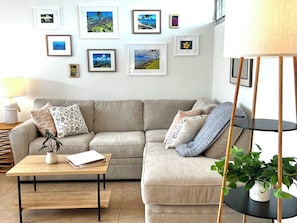 A living room with a sofa, a coffee table, a lamp, and framed pictures on the wall.