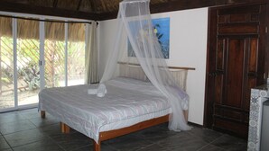A room with a bed, a wooden door, a painting on the wall, and a view of greenery outside. - Ka'ax Cenote Resort (Akumal)
