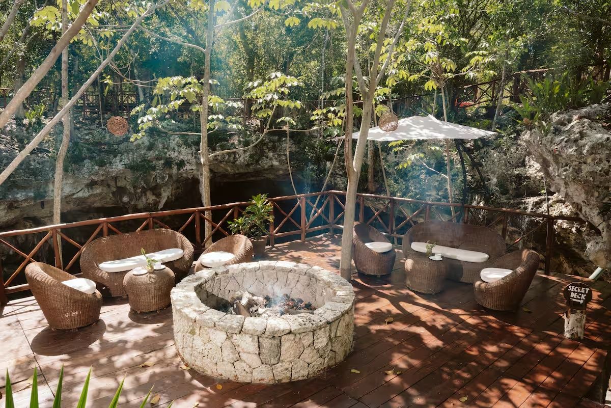 Un espacio de estar al aire libre con mobiliario de mimbre y una chimenea de piedra.