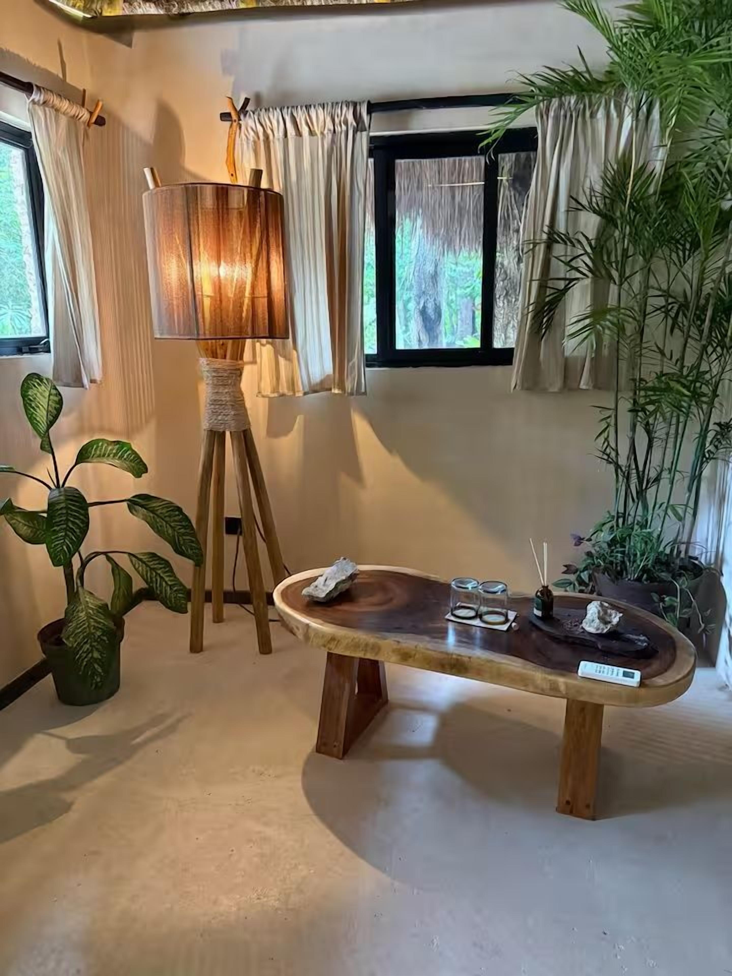 A room with a wooden table, a lamp, and potted plants.