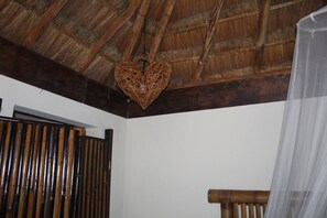 A room with a wooden ceiling, a heart-shaped hanging ornament, a bamboo partition, and a wooden chair. - Ka'ax Cenote Resort (Akumal)
