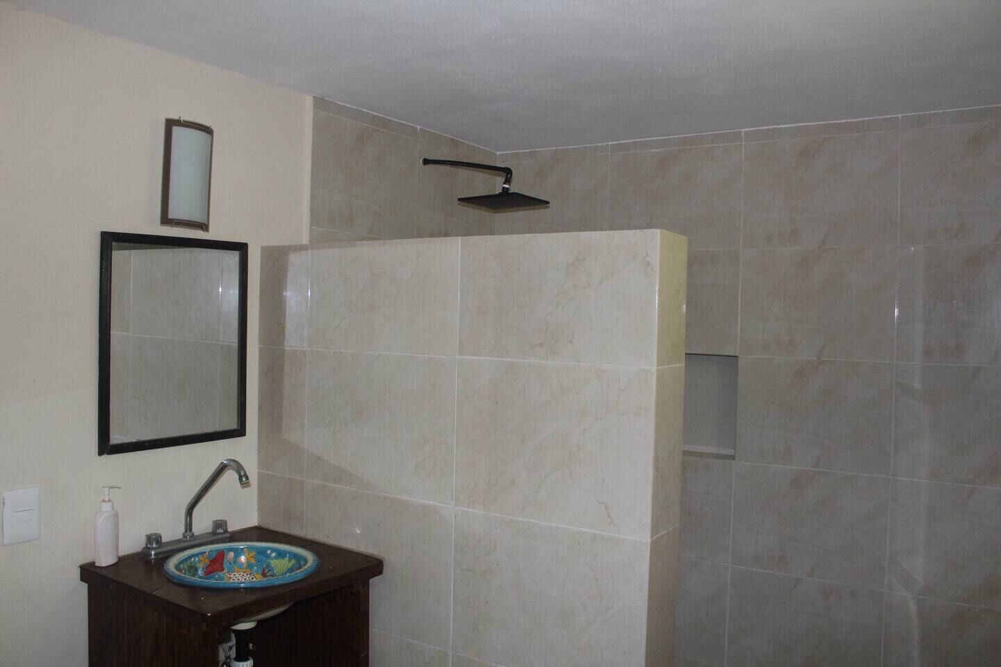 Een badkamer met wastafel, spiegel en douche.
