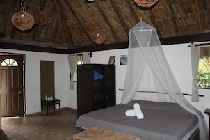 A bedroom with a bed, a wardrobe, a chair, and a window with curtains.