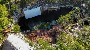 A cliffside view of a natural cave with a wooden deck and seating area overlooking the cave entrance. - Ka'ax Cenote Resort (Akumal)