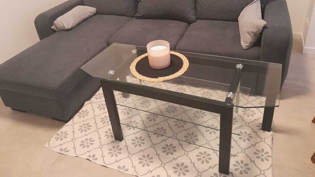 A grey sectional sofa with a glass coffee table and a candle on it. - Location Maison 3 Chambres Circuit des 24H (Le Mans)