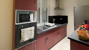 A modern kitchen with a microwave, oven, and stainless steel refrigerator. - Location Maison 3 Chambres Circuit des 24H (Le Mans)