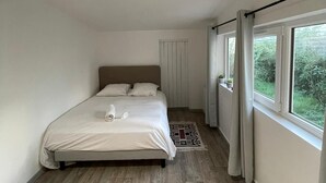 A bedroom with a bed, a radiator, a window with curtains, and a ceiling light fixture. - Location Maison 3 Chambres Circuit des 24H (Le Mans)