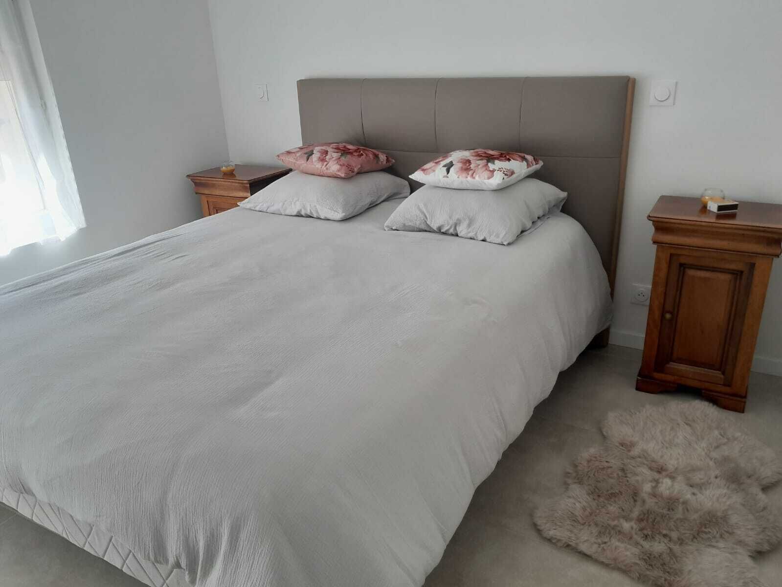 Une chambre à coucher avec un grand lit, deux tables de chevet, une armoire en bois et un tapis moelleux.