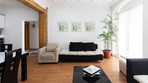 A modern living room with a sofa, a dining table, and chairs. There are three abstract paintings on the wall and a potted plant. - Ste. Presidencial • Steps from the Catedral (Luis Cordero Cuenca)
