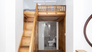 A wooden staircase leading to a loft bedroom with a built-in toilet and shower. - Ste. Presidencial • Steps from the Catedral (Luis Cordero Cuenca)