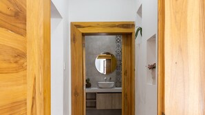 A narrow hallway with wooden doors leading to a bathroom with a sink and mirror. - Ste. Presidencial • Steps from the Catedral (Luis Cordero Cuenca)
