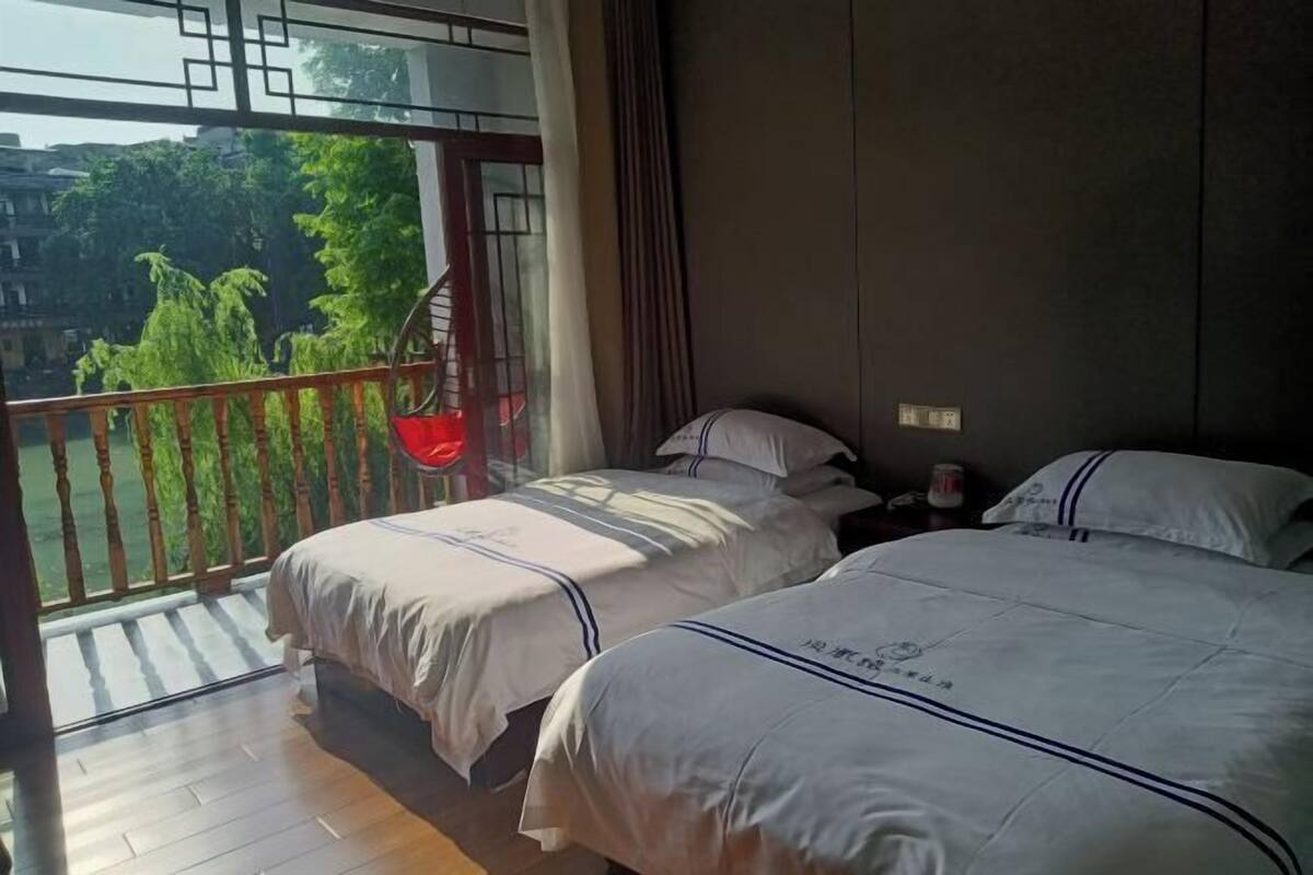 A bedroom with two beds, a balcony with a hanging chair, and a view of greenery outside.
