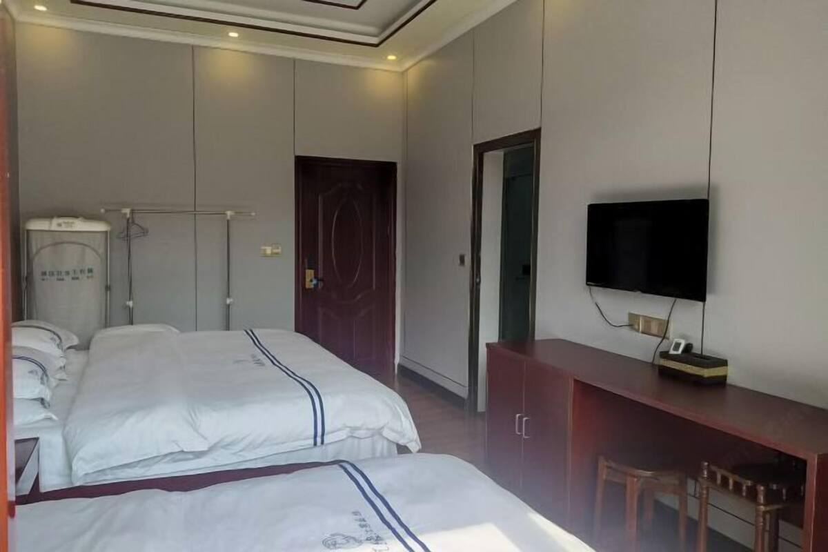 A hotel room with two beds, a television, a desk, and a mirror.
