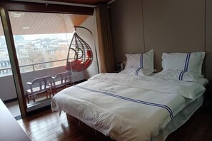 Una habitación de hotel con una cama grande, un sillón colgante junto a la ventana y vistas a la ciudad.