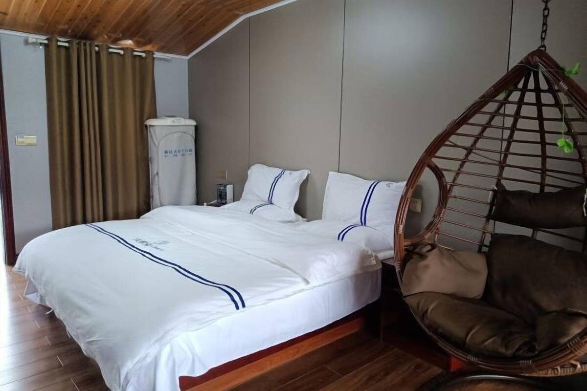 A bedroom with a bed, a hanging chair, and a wardrobe.