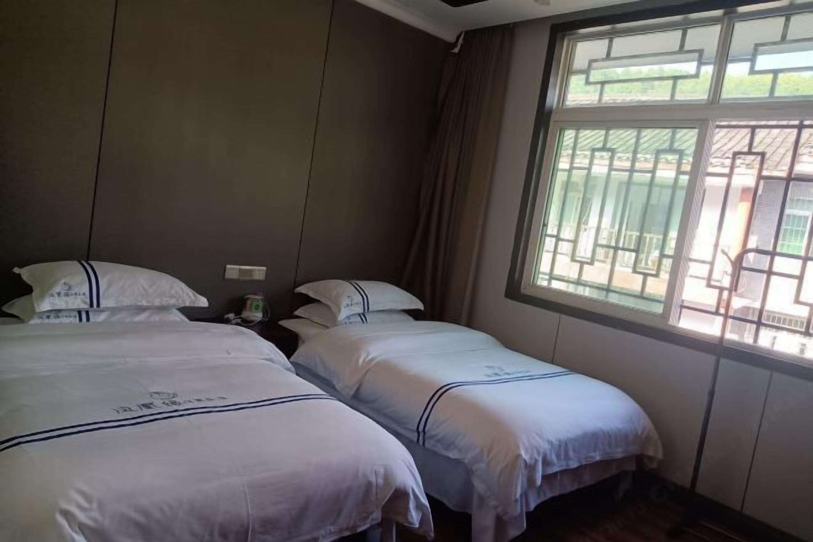 Ein Hotelzimmer mit zwei Betten, einem Fenster mit Blick und einem Vorhang.