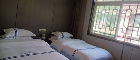 Ein Hotelzimmer mit zwei Betten, einem Fenster mit Blick und einem Vorhang.