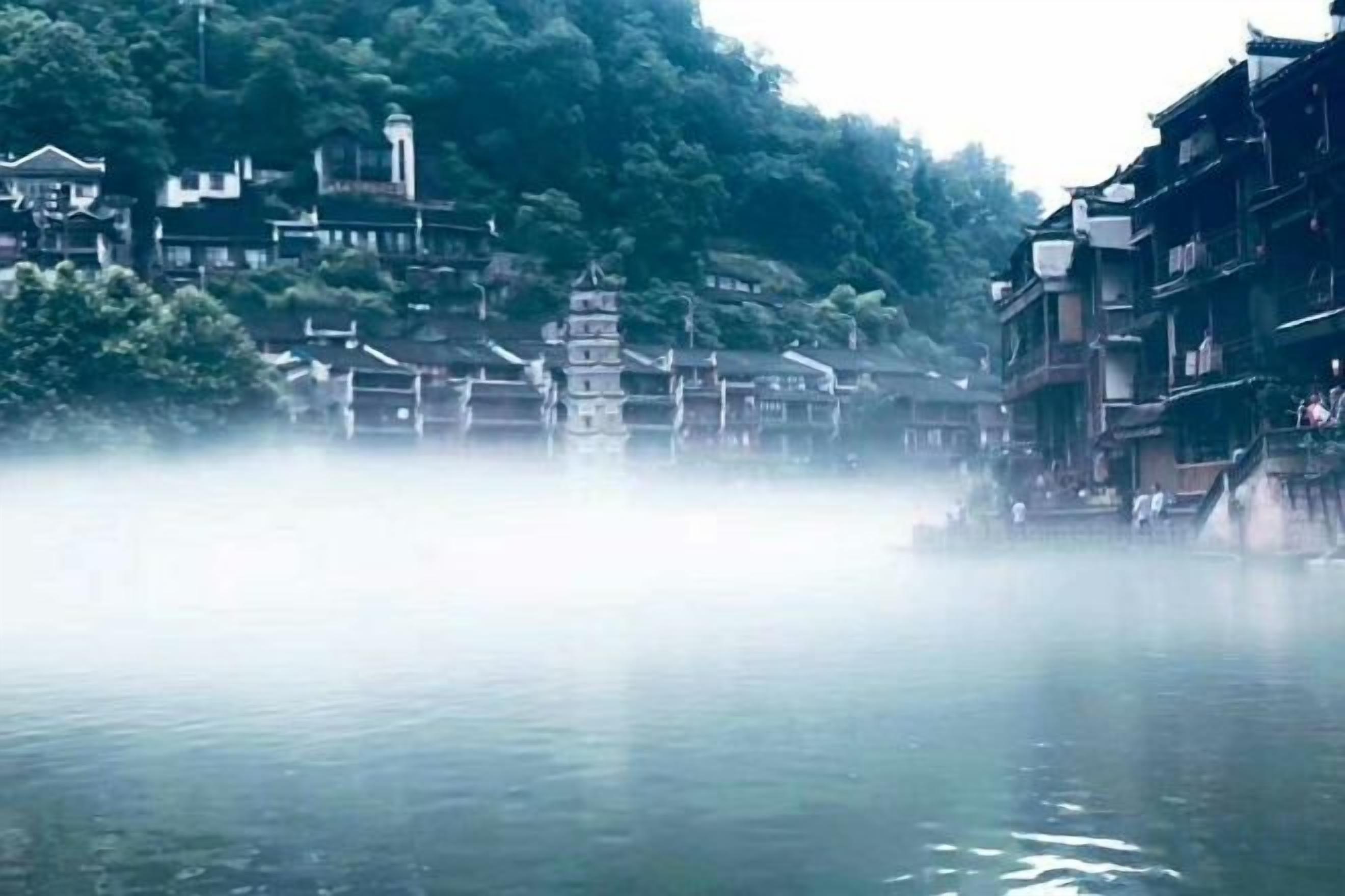 A traditional building with a pagoda-style structure in the center, surrounded by water and dense greenery.