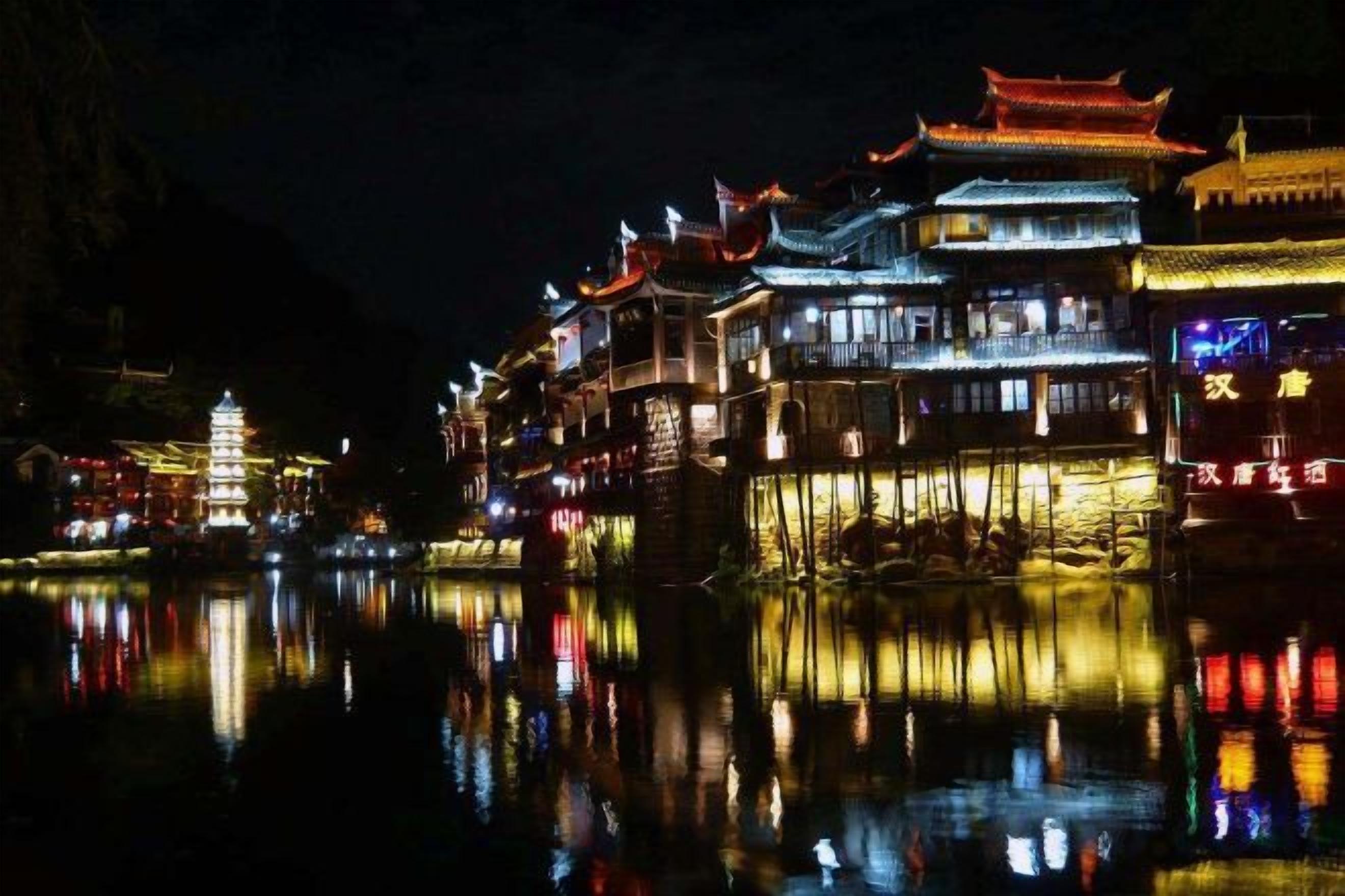 A traditional building with multiple levels, illuminated by artificial lighting, reflecting on the water surface.