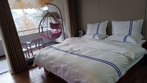 Habitación de hotel con cama, sillón colgante y vistas a la ciudad.