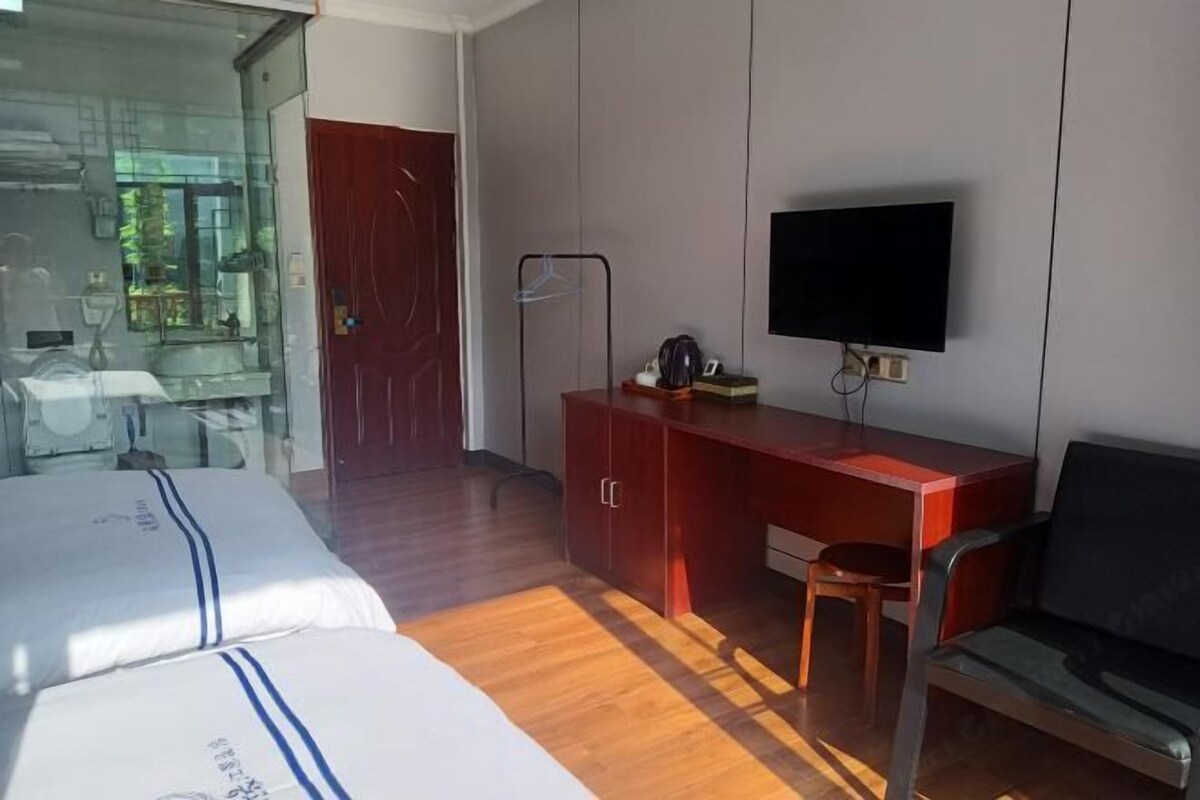 Une chambre d’hôtel avec deux lits, un bureau, une télévision et un canapé.