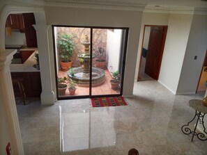 Enjoy a serene atmosphere with a clear view of the outdoor space, featuring a decorative fountain and potted plants, from the comfort of this stylish room.