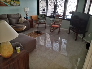 Relax in this inviting living room with a sofa, coffee table, armchair, and TV on a stand, offering a comfortable space to unwind.