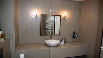 A bathroom with a large mirror, a sink, and two wall-mounted lights.