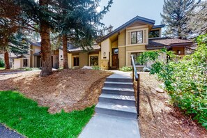 A modern two-story house with a stone foundation, a front porch, and a well-maintained lawn.