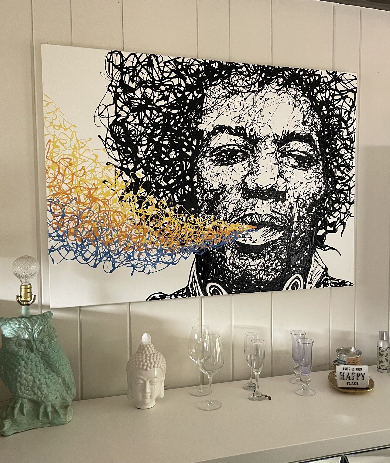 A wall-mounted artwork with a black and white abstract design and colorful splashes at the bottom.
